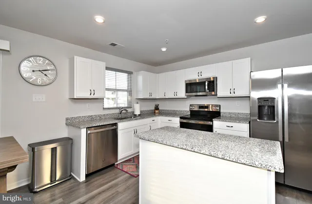 a kitchen with granite countertop stainless steel appliances a stove top oven a refrigerator a sink and dishwasher