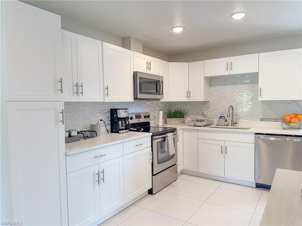 a kitchen with white cabinets sink and appliances