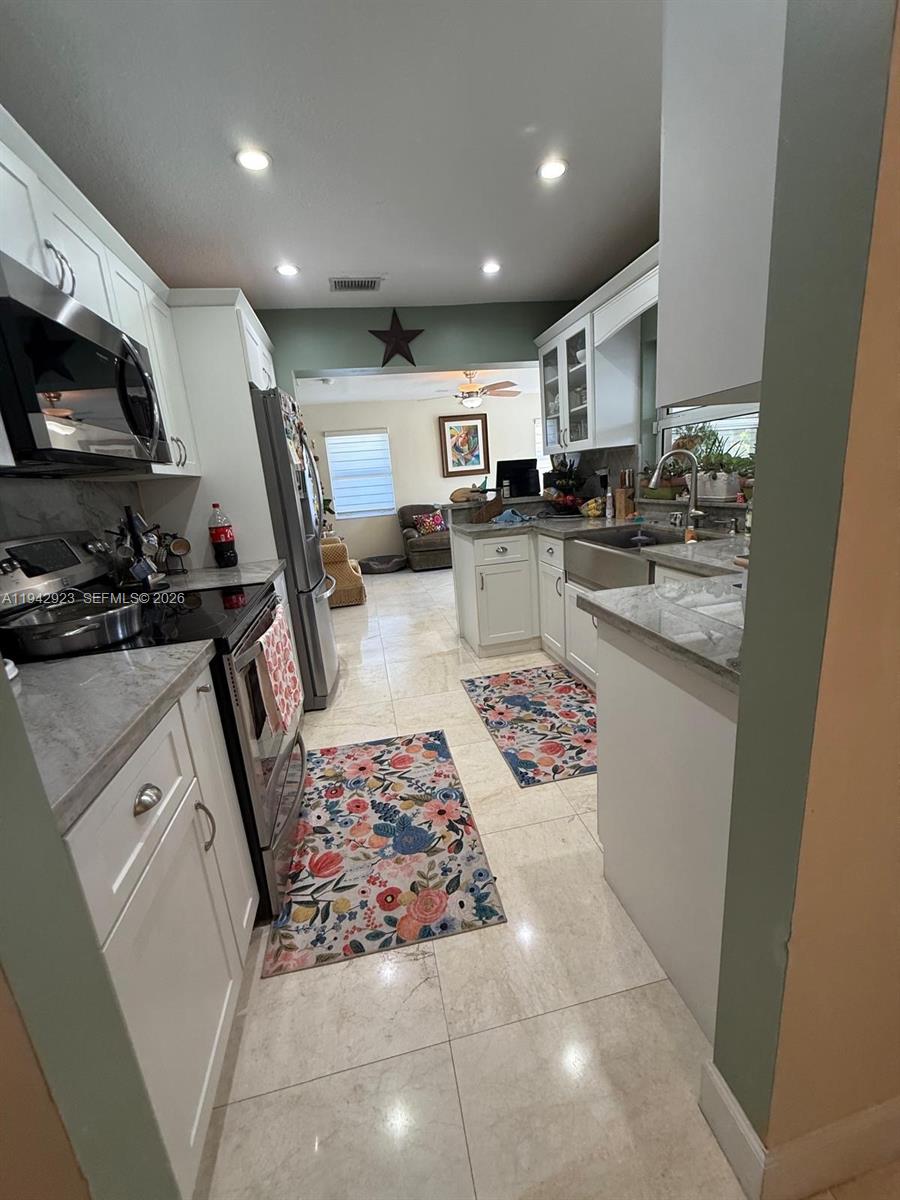 2725 Southwest 102nd Avenue Miami, FL 33165 - Photo 14 of 34 a kitchen with stainless steel appliances kitchen island granite countertop a sink stove and cabinets