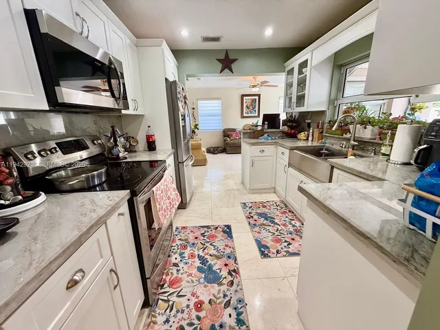 a very nice looking open kitchen with stainless steel appliances granite countertop a stove a sink a microwave and refrigerator
