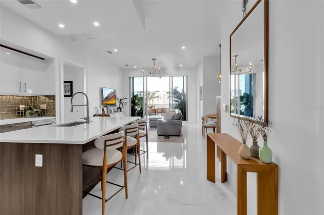 a kitchen with stainless steel appliances granite countertop a stove top oven a sink dishwasher a dining table and chairs with wooden floor