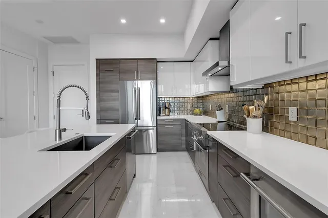 a large kitchen with kitchen island a large counter top space a sink a refrigerator and windows