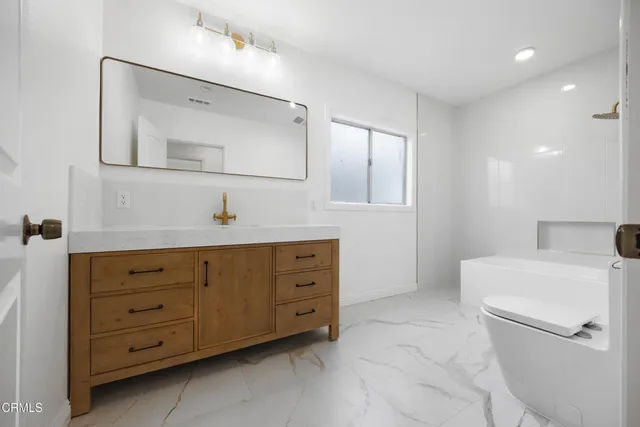 a spacious bathroom with a double vanity sink a mirror and a toilet