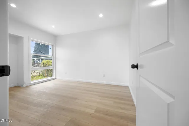 a view of an empty room with window and wooden floor