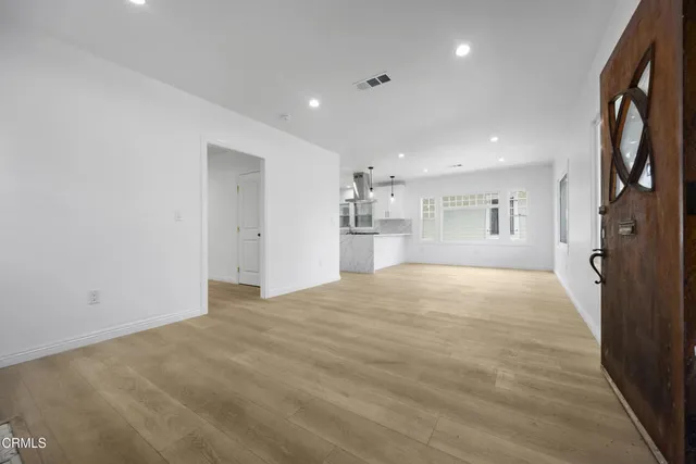 a view of empty room with wooden floor and a window
