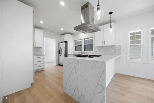a kitchen with stainless steel appliances kitchen island a white counter space and a window