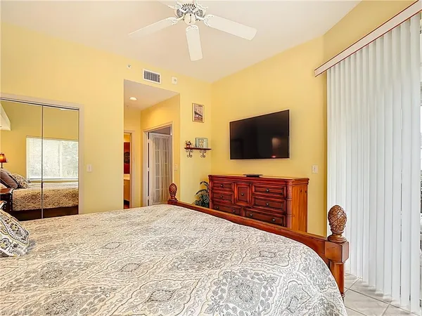 a bedroom with a bed and a flat tv screen on dresser