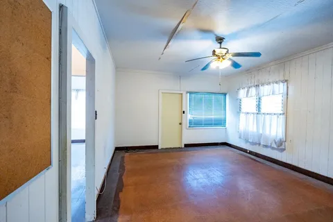 an empty room with windows and chandelier fan