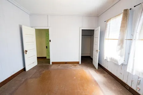 a view of an empty room with window and closet area