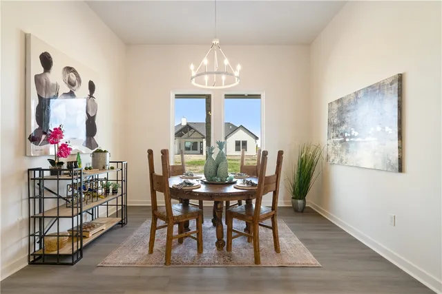 a open kitchen with stainless steel appliances granite countertop a stove top oven a dining table and chairs with wooden floor