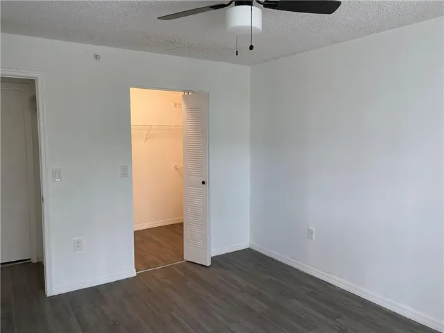 an empty room with wooden floor cabinet and windows