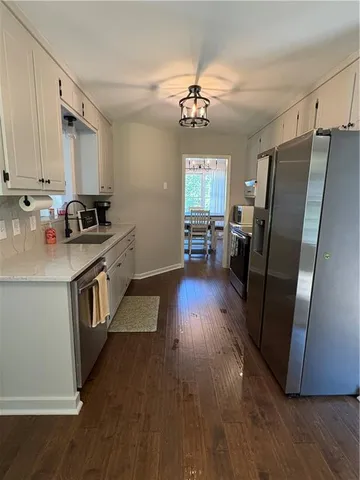 a kitchen with stainless steel appliances granite countertop hardwood floor sink stove dining table and chairs