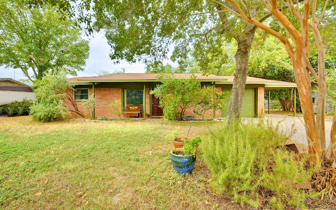 Rear view of house featuring brick siding, a lawn, and an attached garage