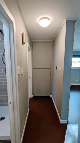 a view of a hallway with wooden floor and a bathroom
