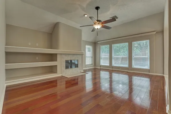 a view of an empty room with a window and wooden floor