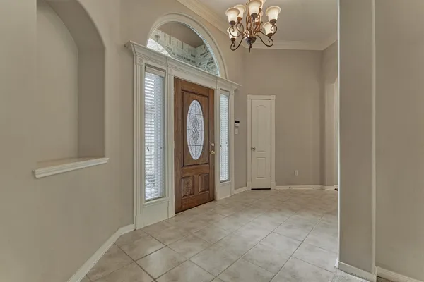 an empty room with chandelier front door