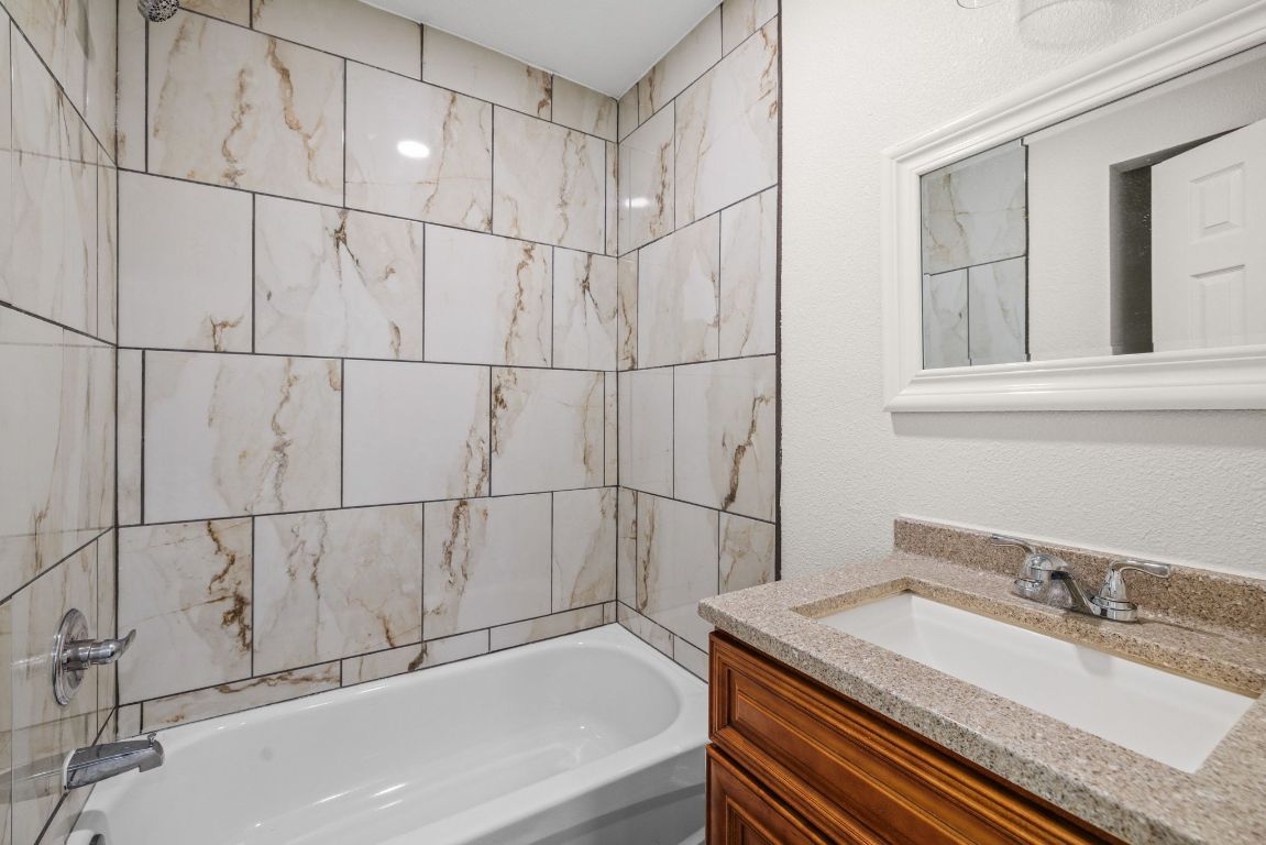 1308 South 45th Street Temple, TX 76504 - Photo 18 of 26 Bathroom featuring vanity, a textured wall, and shower / bath combination