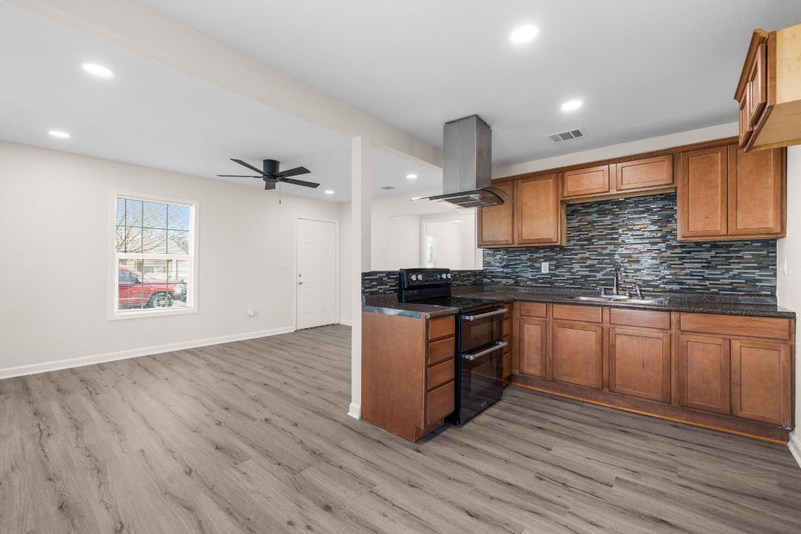 1308 South 45th Street Temple, TX 76504 - Photo 6 of 26 Kitchen with brown cabinetry, double oven range, island range hood, a ceiling fan, and tasteful backsplash