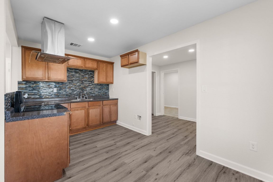 1308 South 45th Street Temple, TX 76504 - Photo 7 of 26 Kitchen featuring brown cabinetry, decorative backsplash, recessed lighting, island range hood, and dark stone countertops