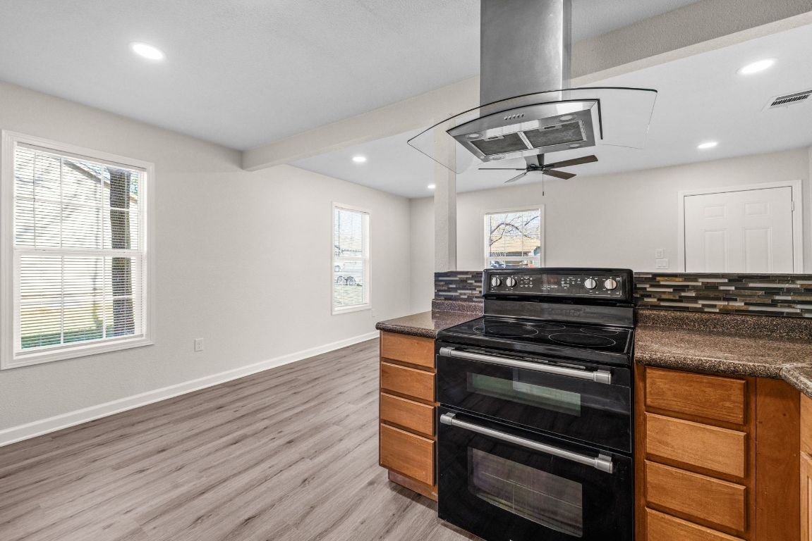 1308 South 45th Street Temple, TX 76504 - Photo 9 of 26 Kitchen featuring double oven range, island range hood, brown cabinets, recessed lighting, and light wood-style flooring
