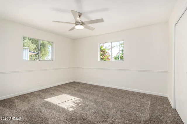 an empty room with windows and fan