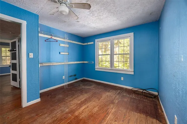 a view of empty room with wooden floor and fan