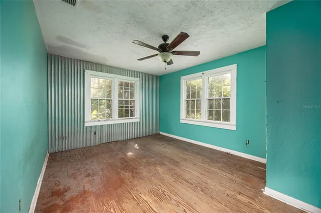 a view of an empty room with a window and wooden floor