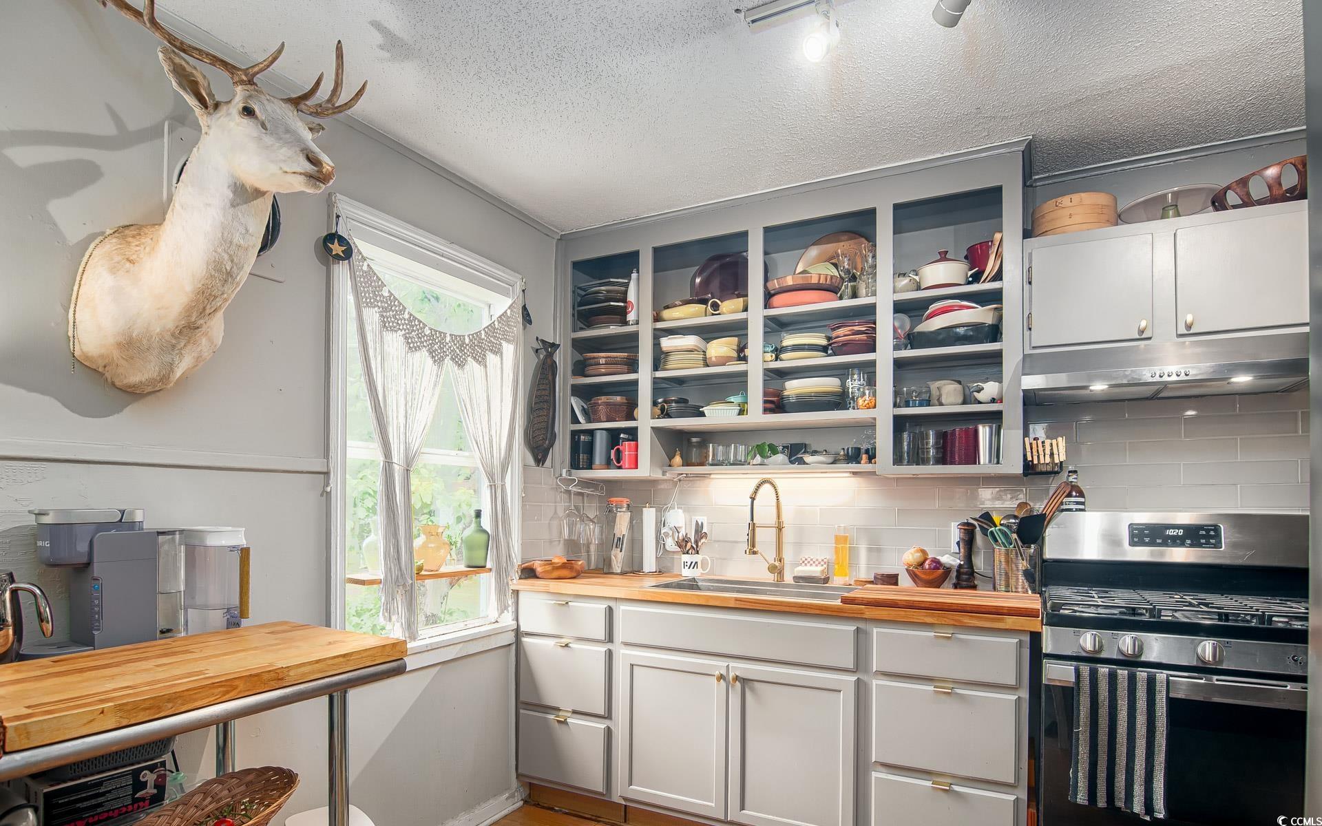640 Willow Bank Road Georgetown, SC 29440 - Photo 10 of 18 Kitchen with stainless steel gas stove, under cabinet range hood, a sink, butcher block countertops, and a textured ceiling