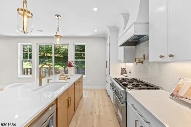 a kitchen with stainless steel appliances granite countertop a sink a stove and a wooden floors