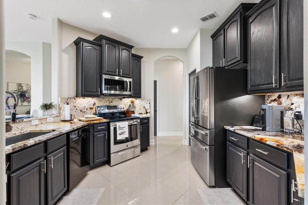 12114 Eagle Point Court Leesburg, FL 34788 - Photo 12 of 39 a kitchen with stainless steel appliances granite countertop a stove refrigerator and microwave