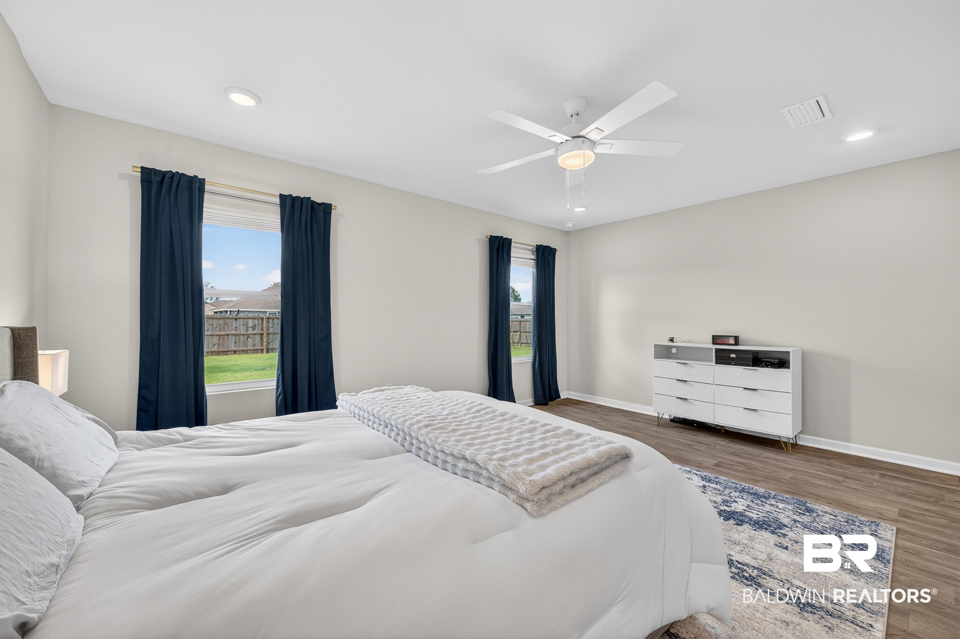 3213 Camino Real Loop Lillian, AL 36549 - Photo 38 of 61 Spacious room featuring wood-finish flooring, two windows with dark drapery, a ceiling fan with integrated lighting, and recessed ceiling lights