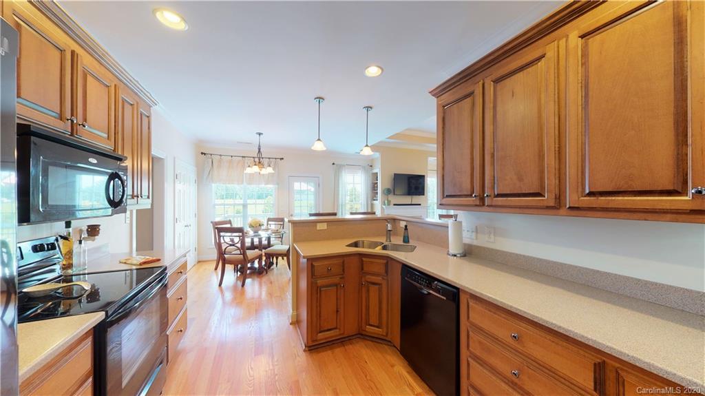 3812 Zebulon Williams Road Monroe, NC 28110 - Photo 9 of 31 a kitchen with stainless steel appliances granite countertop a stove top oven a sink dishwasher a dining table and chairs with wooden floor