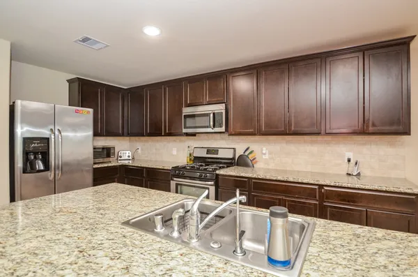 a kitchen with granite countertop wooden cabinets a refrigerator and a sink