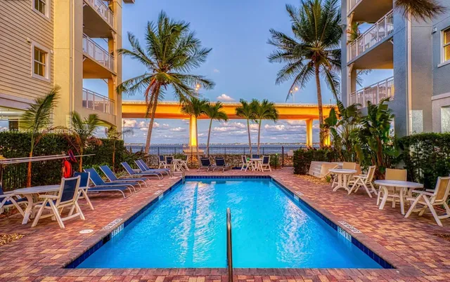 a view of a swimming pool with a lounge chair and palm trees