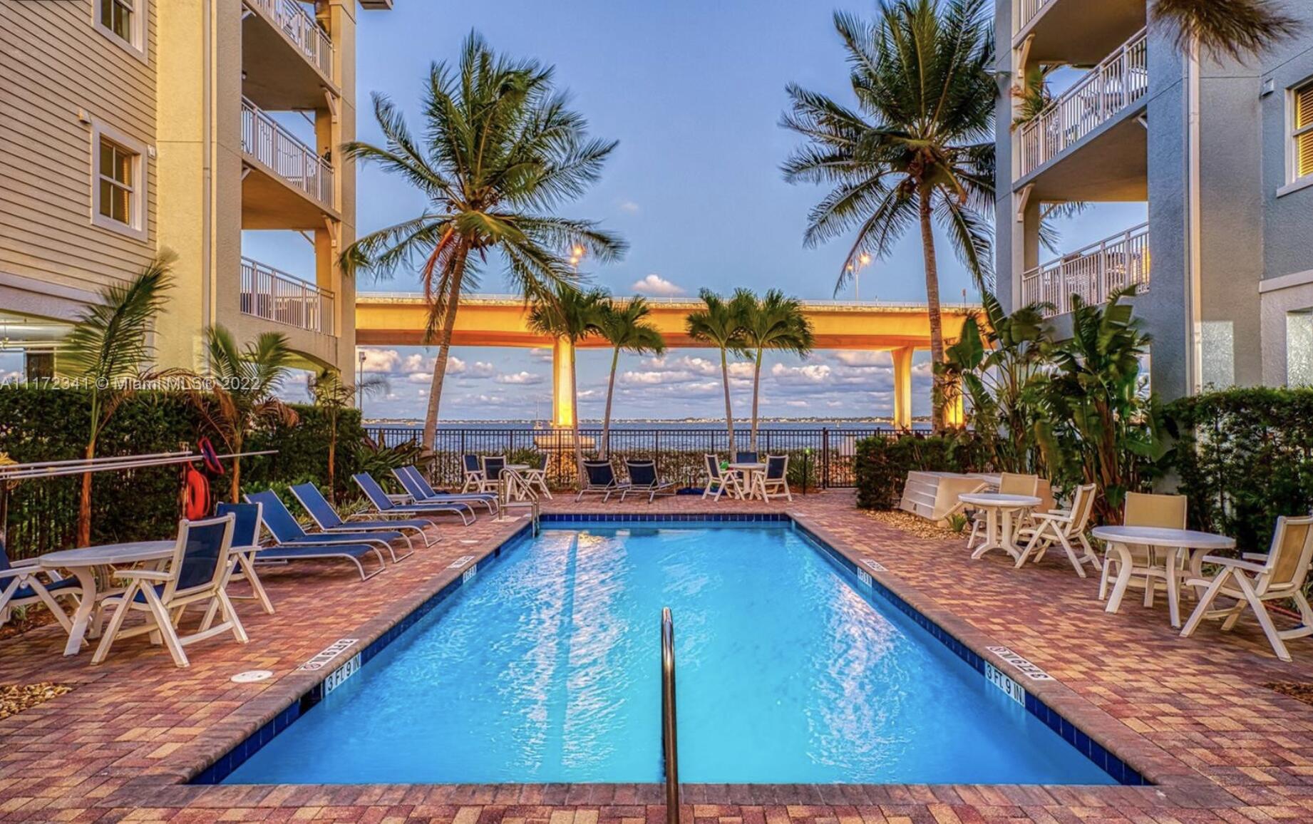 215 Northwest Flagler Avenue, Unit 301 Stuart, FL 34994 - Photo 1 of 34 a view of a swimming pool with a lounge chair and palm trees