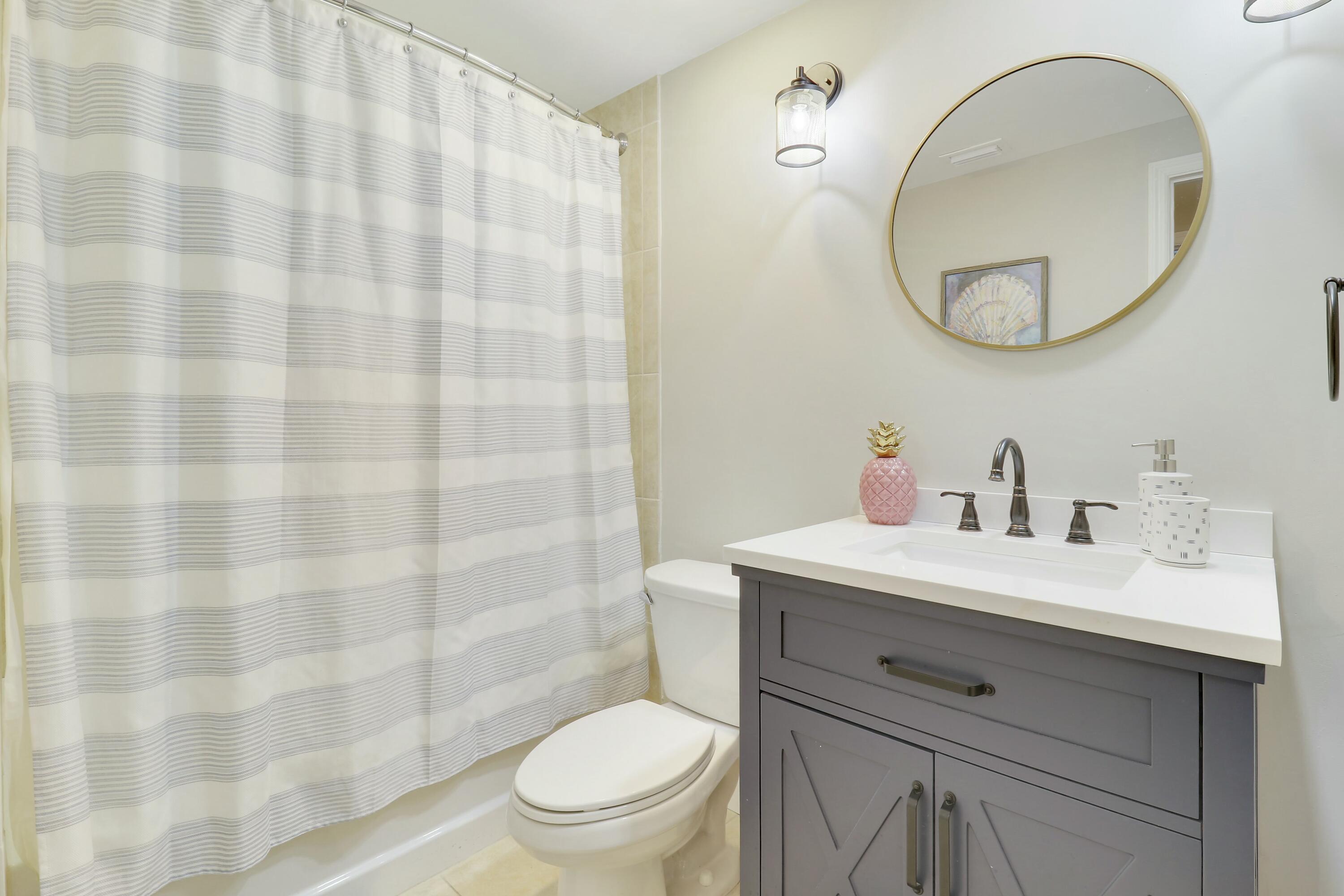 215 Northwest Flagler Avenue, Unit 301 Stuart, FL 34994 - Photo 31 of 34 a bathroom with a sink toilet a mirror and shower curtain