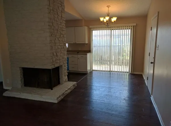 an empty room with wooden floor fireplace and windows