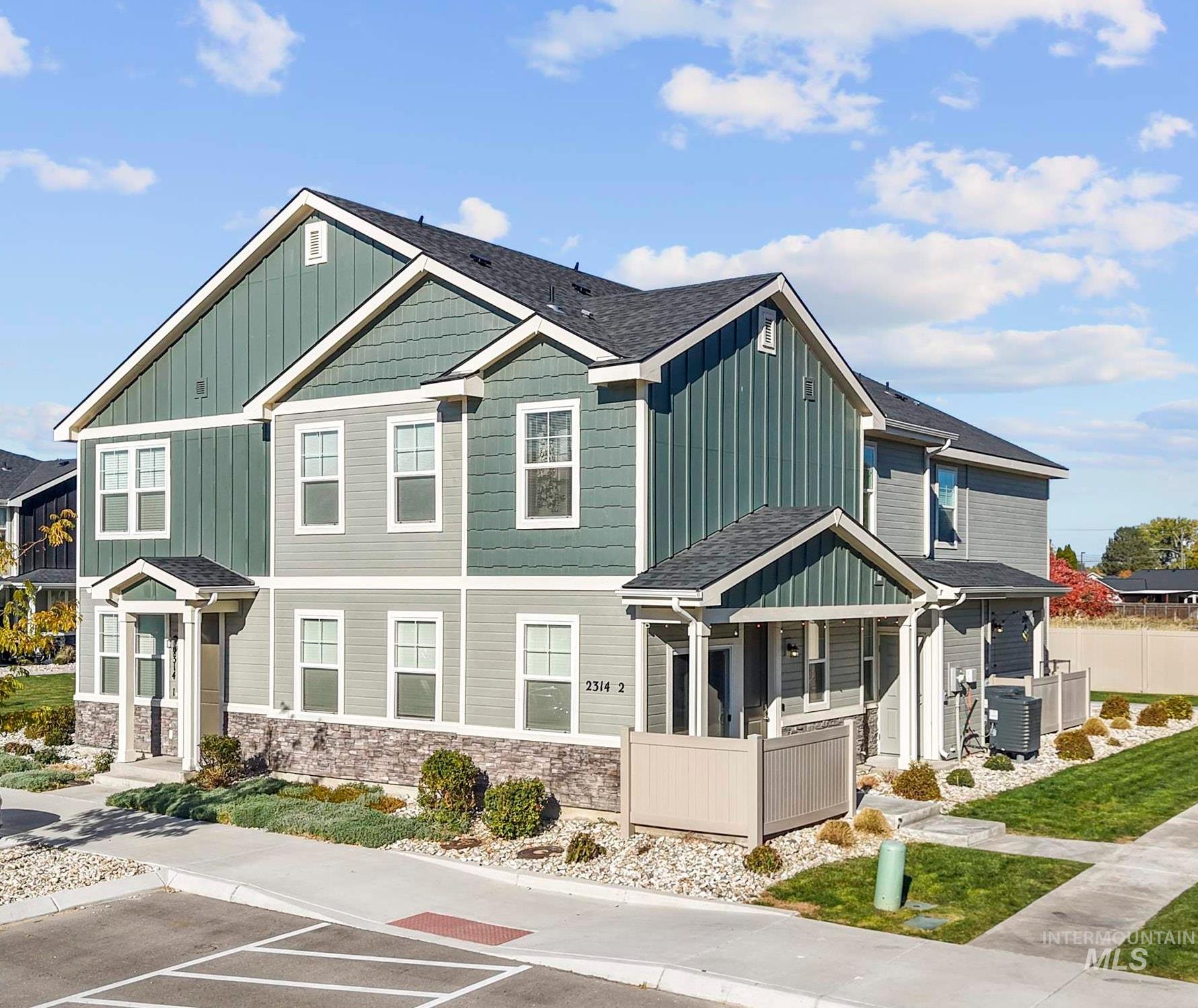 View of front of home featuring board and batten siding, uncovered parking, stone siding, and a shingled roof