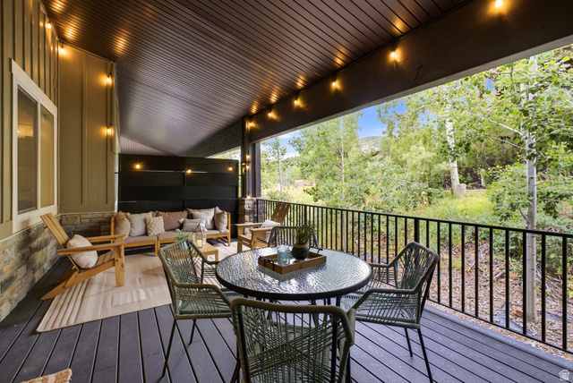 3355 Santa Fe Road Park City, UT 84098 - Photo 24 of 45 Expansive covered deck featuring composite wood-finish flooring, a stone accent wall, and a black metal railing