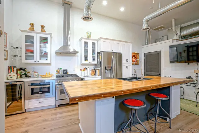 a kitchen with stainless steel appliances kitchen island granite countertop a table chairs in it and wooden floors