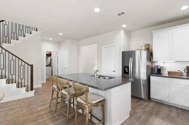 a kitchen with stainless steel appliances a refrigerator a stove a dining table and chairs