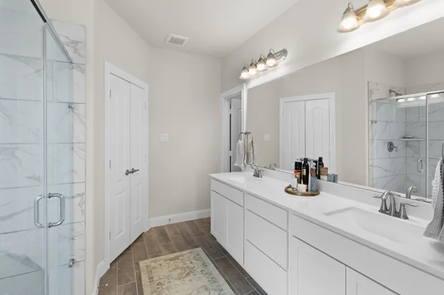 a bathroom with a double vanity sink mirror and shower