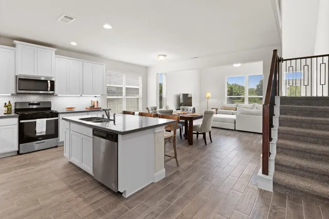 a kitchen with stainless steel appliances kitchen island granite countertop a stove top oven a sink a dining table and chairs