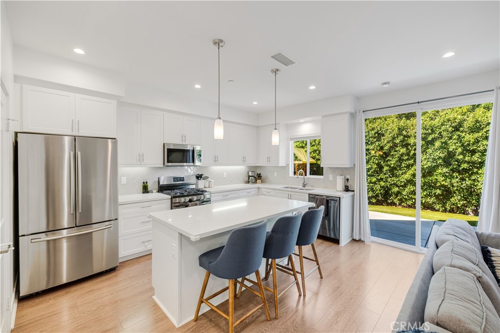 6747 Rhea Court Reseda, CA 91335 - Photo 3 of 26 a kitchen with stainless steel appliances kitchen island granite countertop a refrigerator a stove a sink dishwasher a dining table and chairs with wooden floor