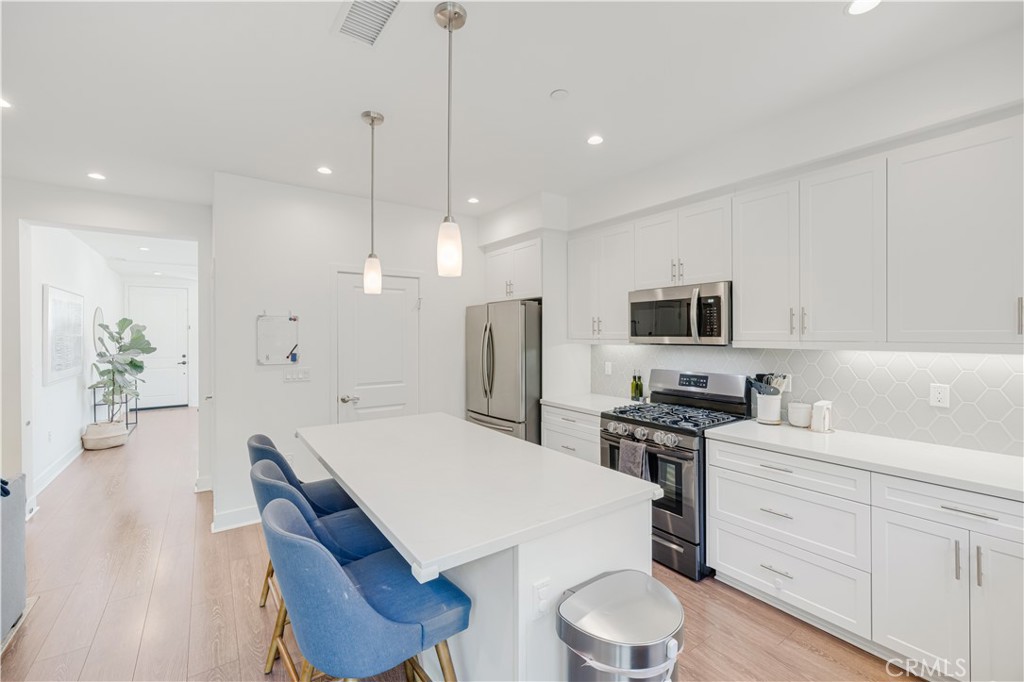 6747 Rhea Court Reseda, CA 91335 - Photo 4 of 26 a kitchen with stainless steel appliances a stove a sink a microwave a refrigerator white cabinets and chairs