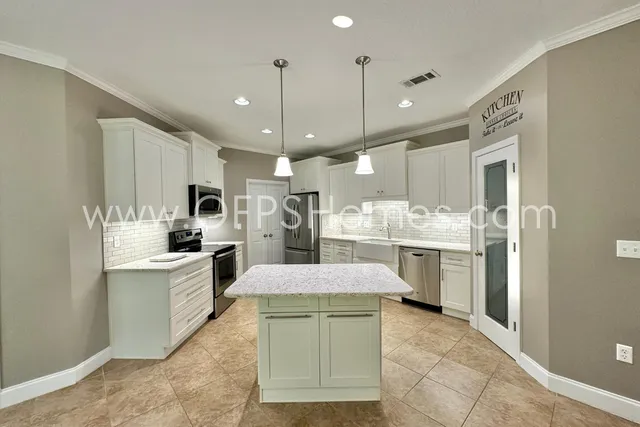 a large kitchen with white cabinets and stainless steel appliances