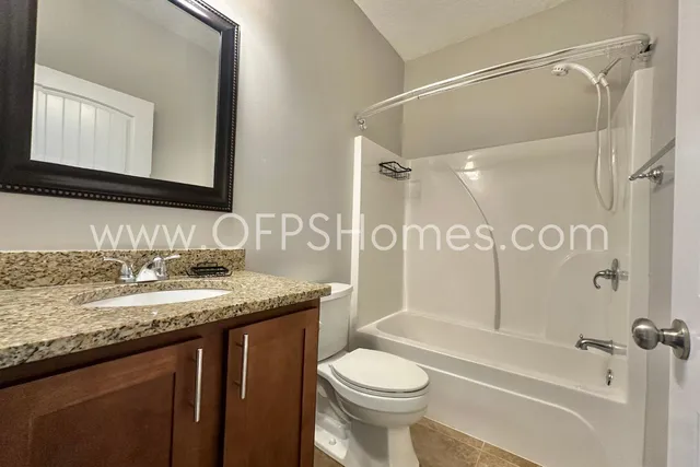 a bathroom with a granite countertop sink toilet mirror and shower