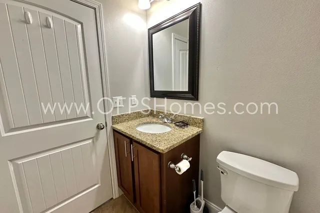 a bathroom with a granite countertop sink and a toilet