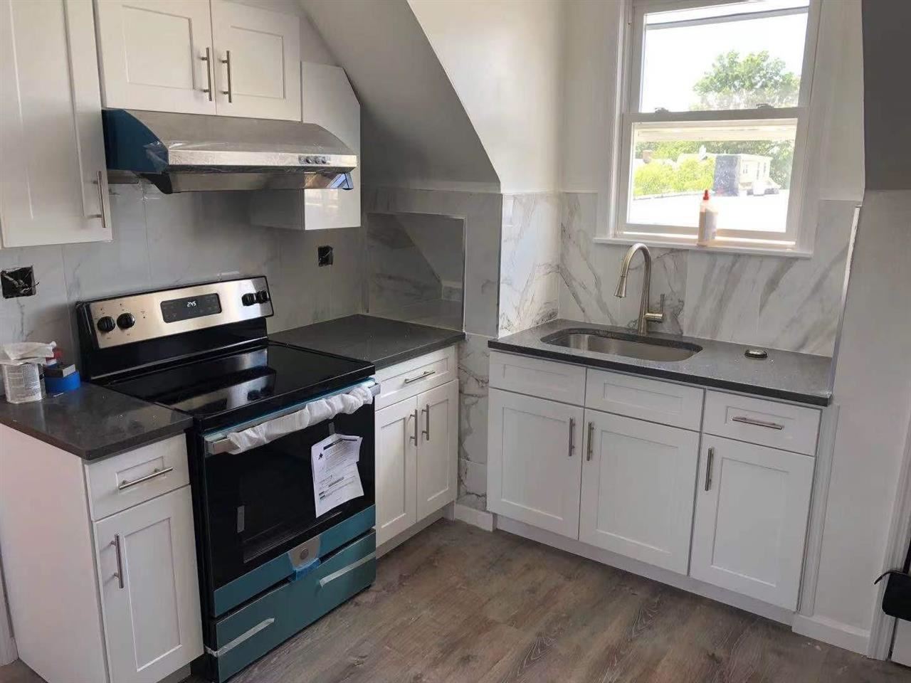 a kitchen with stainless steel appliances granite countertop white cabinets and a stove a sink