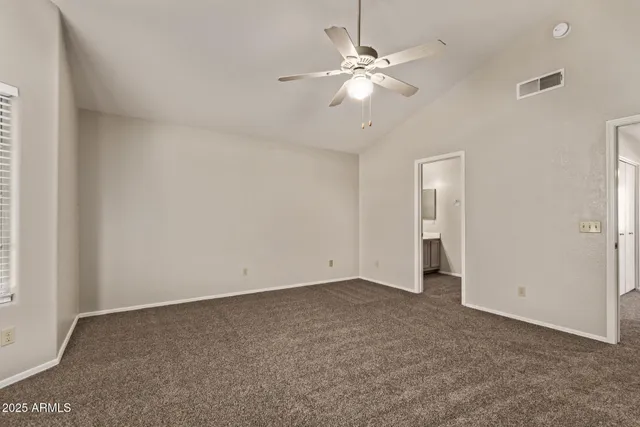 an empty room with a chandelier fan and windows